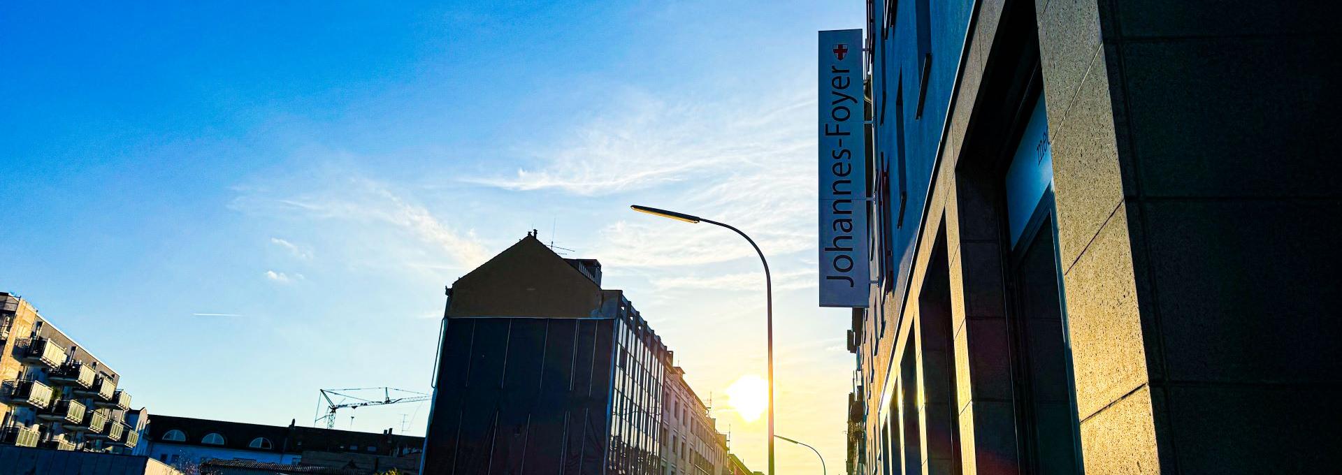 Man blickt in eine Straße vom Johannes-Foyer aus. Am Ende der Straße strahlt die Sonne