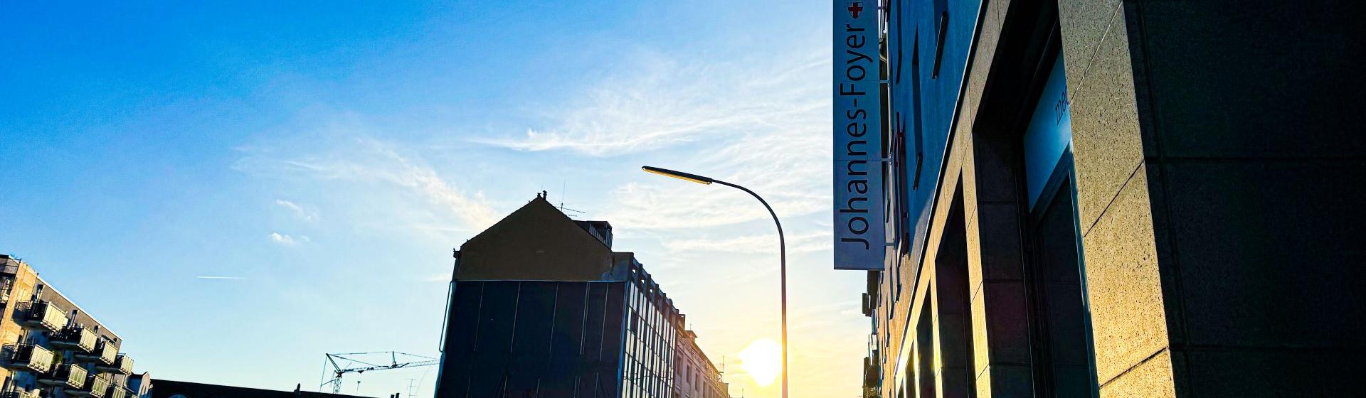 Man blickt in eine Straße vom Johannes-Foyer aus. Am Ende der Straße strahlt die Sonne