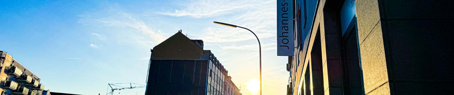 Man blickt in eine Straße vom Johannes-Foyer aus. Am Ende der Straße strahlt die Sonne