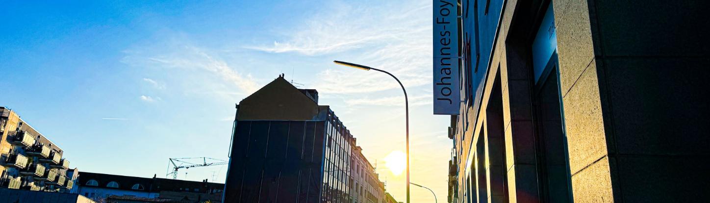 Man blickt in eine Straße vom Johannes-Foyer aus. Am Ende der Straße strahlt die Sonne